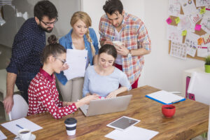 Content marketing team brainstorming ideas around a laptop during a strategy meeting.